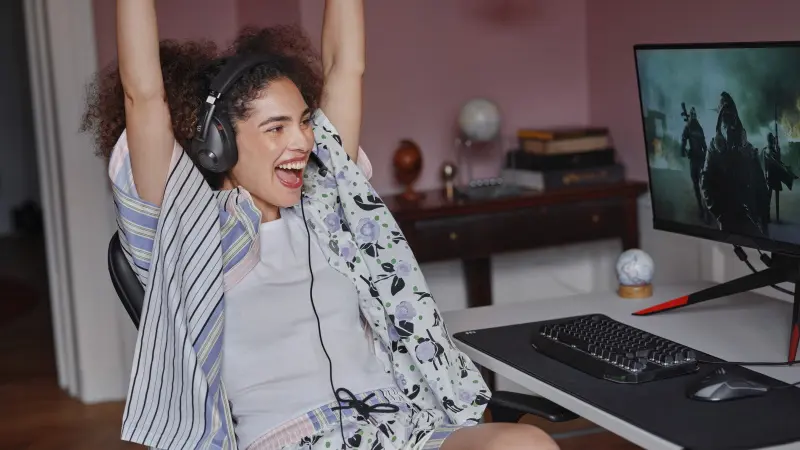 A woman celebrating her game whilst wearing the EPOS H3 Hybrid Black headset.